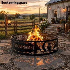May include: A circular black metal fire pit ring featuring laser-cut silhouettes of owls, pine trees, and mountains. The metal panels include the text "CUSTOM NAME" and "ENCHANTINGSPACE" with a bright orange fire burning inside the center.