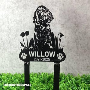 Könnte beinhalten: Schwarzer Metall-Gartenstecker mit einer Hundesilhouette, dem Namen "WILLOW" und den Jahren "2021-2025". Der Stecker hat Pfotenabdrücke und florale Details. Der Text "ENCHANTINGSPACE" befindet sich unten.