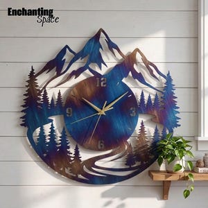 May include: A circular metal wall clock featuring a mountain and pine forest silhouette with a heat-treated blue and bronze finish. The clock face displays the numbers 3, 6, 9, and 12 in a metallic font with thin gold-toned clock hands.