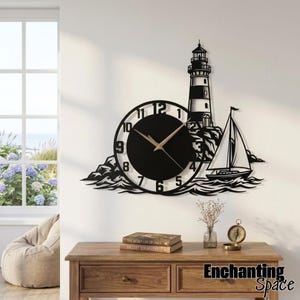 May include: A black metal wall clock featuring a lighthouse, a sailboat, and rocky waves. The circular clock face has white numbers from one to twelve and gold-colored hands. The design is mounted on a wall above a wooden console table.