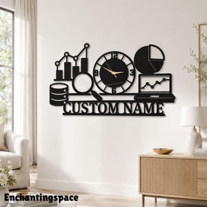 Puede incluir: Un reloj de pared negro con iconos de análisis de datos que incluyen un gráfico de barras, una lupa, un gráfico circular y un portátil con un gráfico lineal. La esfera tiene manecillas doradas y el texto CUSTOM NAME en fuente serif.