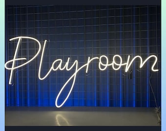 Op de afbeelding: Een wit neonbord met het woord "Playroom" in een cursief schrift tegen een blauwe rasterachtergrond.