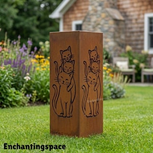 Puede incluir: Escultura de jardín rectangular de metal envejecido con diseño de gato. La escultura tiene un acabado marrón, similar al óxido, y representa tres gatos apilados. El texto "Enchantingspace" está en la parte inferior.
