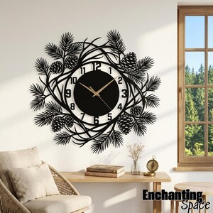 May include: A circular wall clock featuring a black metal frame with a decorative cutout design of pine branches and pinecones. The clock face has a white background with black numerals from 1 to 12 and thin gold-colored clock hands.