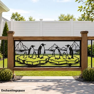 May include: A rectangular black metal decorative panel featuring a laser-cut design of six penguins standing on two ice floes against a backdrop of mountains. The panel is mounted within a wooden frame, displaying the text Enchantingspace.
