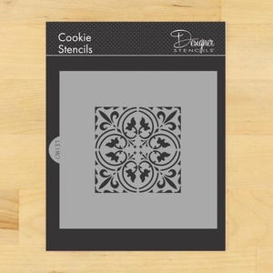 Peut inclure: Un pochoir à biscuits avec un fond gris et un motif floral décoratif noir. Le pochoir est étiqueté "Cookie Stencils" et "Designer Stencils". Le motif est un carré avec un motif symétrique répétitif.