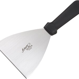 May include: A stainless steel spatula with a black handle. The blade has the text "Ateco Ultima 91310" printed on it.