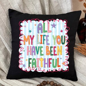 May include: Black square pillow with the text "ALL MY LIFE YOU HAVE BEEN FAITHFUL" in colorful letters. The text is set against a light blue and white striped background, framed by a pink, wavy border and stars.