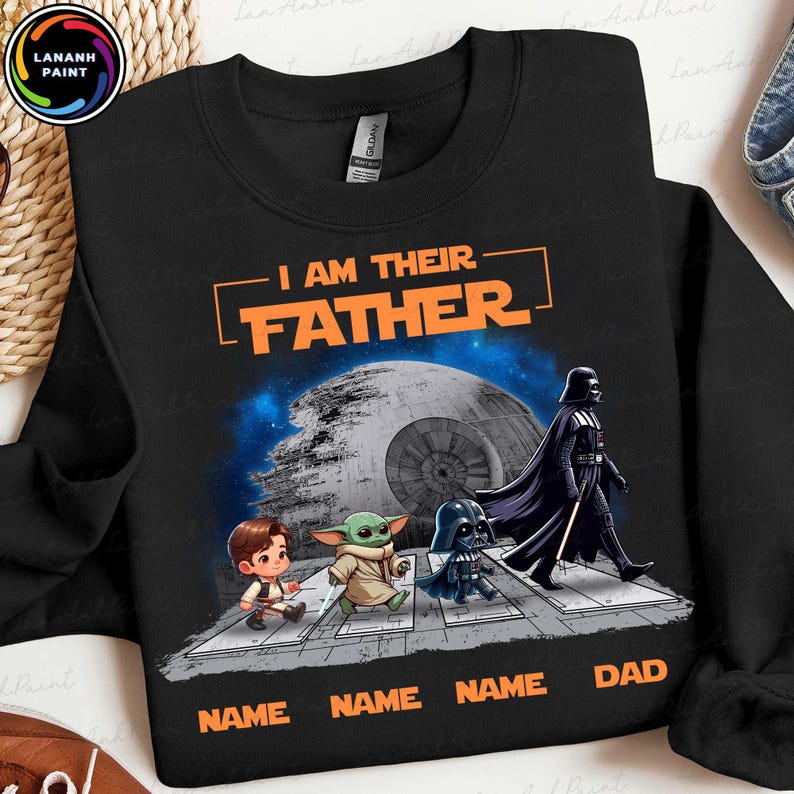 May include: Black sweatshirt with the text "I AM THEIR FATHER" in orange. The design features cartoon characters, including Darth Vader, and the text "NAME NAME NAME DAD" at the bottom. A Death Star is in the background.