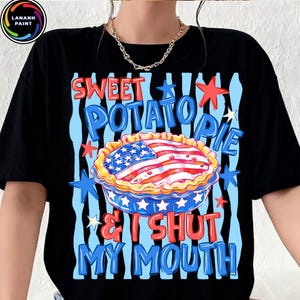May include: Black t-shirt with a graphic of a sweet potato pie decorated with an American flag design. The text reads "Sweet Potato Pie & I Shut My Mouth" in red and blue.