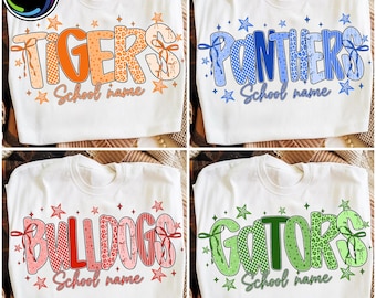 May include: A white t-shirt featuring four variations of a graphic design with the words TIGERS, PANTHERS, BULLDOGS, and GATORS. Each word is styled with patterned letters, bows, and stars, accompanied by the text School name below each.