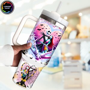 May include: A white tumbler with a handle, featuring a colorful illustration of Jack Skellington and Sally from The Nightmare Before Christmas. The design includes bats, spiderwebs, and a pink and purple background. The tumbler has a white lid and a straw.