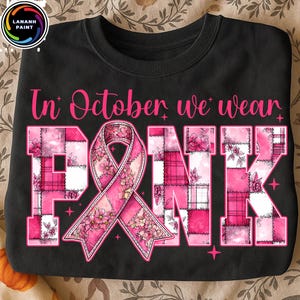 May include: Black sweatshirt with the text "In October we wear PINK". The word PINK is designed with a pink ribbon and floral patchwork pattern. The sweatshirt is a crew neck style.