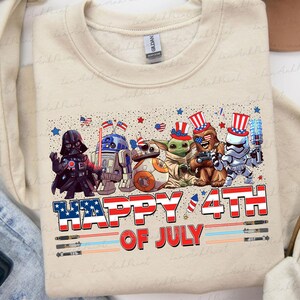 K&ouml;nnte beinhalten: Beiges Sweatshirt mit einer Grafik von Star Wars-Charakteren in patriotischer Kleidung, darunter Darth Vader und Baby Yoda, die den 4. Juli feiern. Der Text "HAPPY 4TH OF JULY" ist deutlich sichtbar.