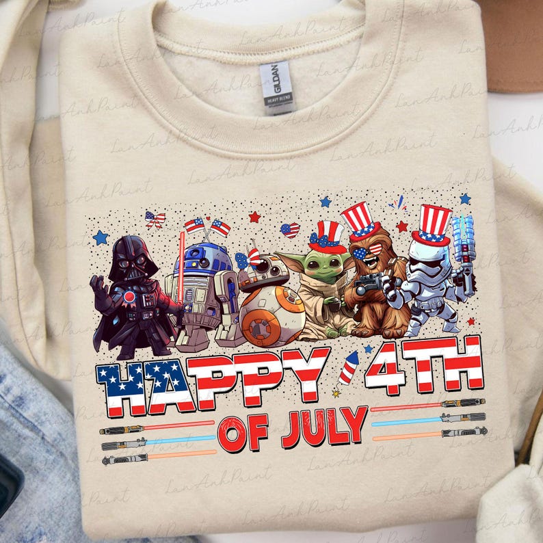K&ouml;nnte beinhalten: Beiges Sweatshirt mit einer Grafik von Star Wars-Charakteren in patriotischer Kleidung, darunter Darth Vader und Baby Yoda, die den 4. Juli feiern. Der Text "HAPPY 4TH OF JULY" ist deutlich sichtbar.