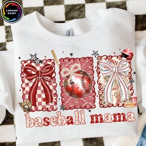 Puede incluir: Sudadera blanca con un diseño de béisbol. Presenta tres cuadrados decorativos con un lazo rojo, una pelota de béisbol con estampado de leopardo y una pelota de béisbol con un lazo. El texto "baseball mama" está impreso en rojo.