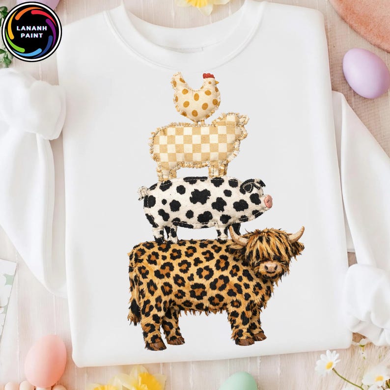 Op de afbeelding: Witte sweatshirt met een ontwerp van gestapelde boerderijdieren: een kip, een schaap, een varken en een koe. De koe heeft een luipaardprint, het varken heeft zwarte vlekken, het schaap heeft een geruit patroon en de kip heeft stippen. De sweatshirt heeft lange mouwen.
