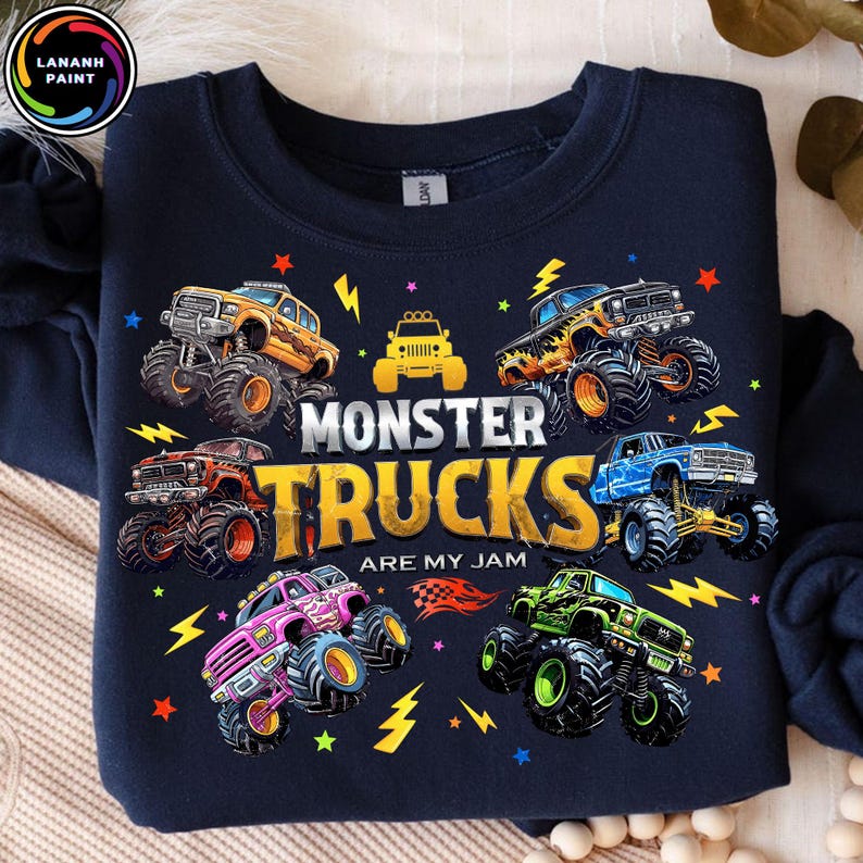 K&ouml;nnte beinhalten: Marineblaues Sweatshirt mit einem farbenfrohen Grafikdesign von Monstertrucks. Der Text "MONSTER TRUCKS ARE MY JAM" ist in gro&szlig;en Buchstaben dargestellt. Blitze und Sterne umgeben die Trucks und erzeugen ein dynamisches Design.