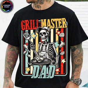 May include: Black t-shirt featuring a skeleton grilling with the words "GRILL MASTER DAD" in a retro design. The skeleton wears a chef's hat and apron, holding a spatula. The design includes stars and food illustrations.