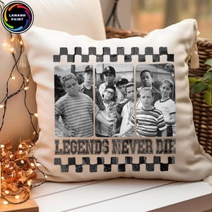 May include: Cream-colored throw pillow featuring a black and white image of a group of people. The image is framed with a checkered pattern and the text "LEGENDS NEVER DIE" in a bold font.