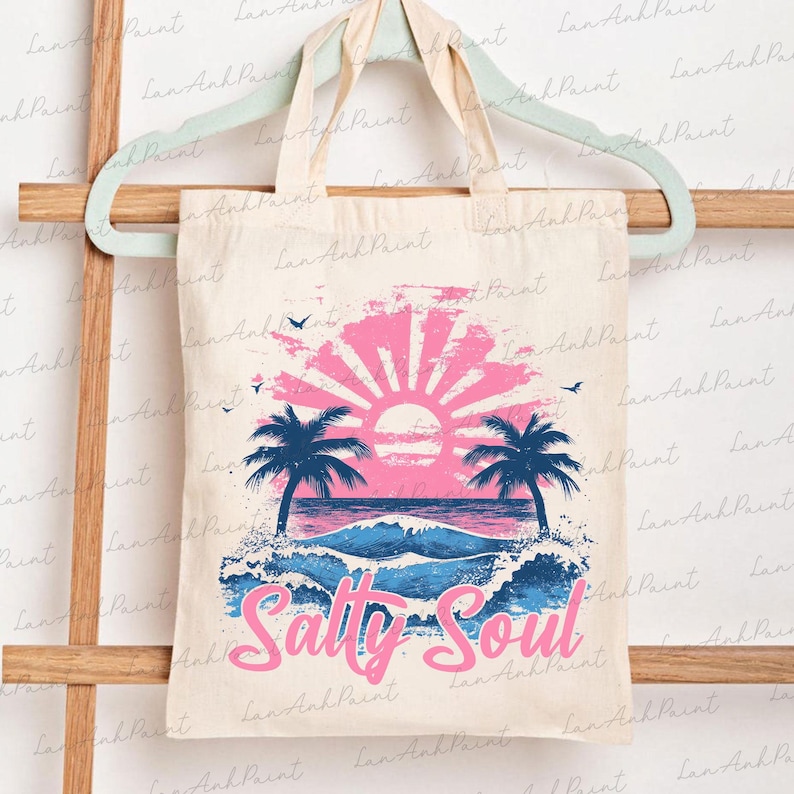 Pu&ograve; includere: Una borsa tote bianca con una grafica di tramonto rosa e blu e palme. Il testo "Salty Soul" &egrave; stampato in rosa sulla borsa.