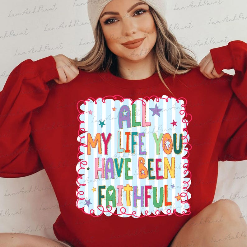 May include: A red sweatshirt with the text "ALL MY LIFE YOU HAVE BEEN FAITHFUL" in colorful letters. The text is inside a white and blue striped frame with stars. The sweatshirt is a solid red color.