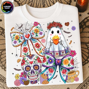 May include: White sweatshirt featuring a colorful Dia de los Muertos design. The design includes a sugar skull, a ghost holding a heart, and floral bows. The design also includes bats, flowers, and a spider web.
