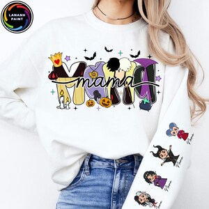 May include: White sweatshirt with the word "Mama" in a Halloween-themed design. The design incorporates cartoon images of villains, bats, pumpkins, and stars. The sleeve features cartoon villain characters with the word "Name" below each.