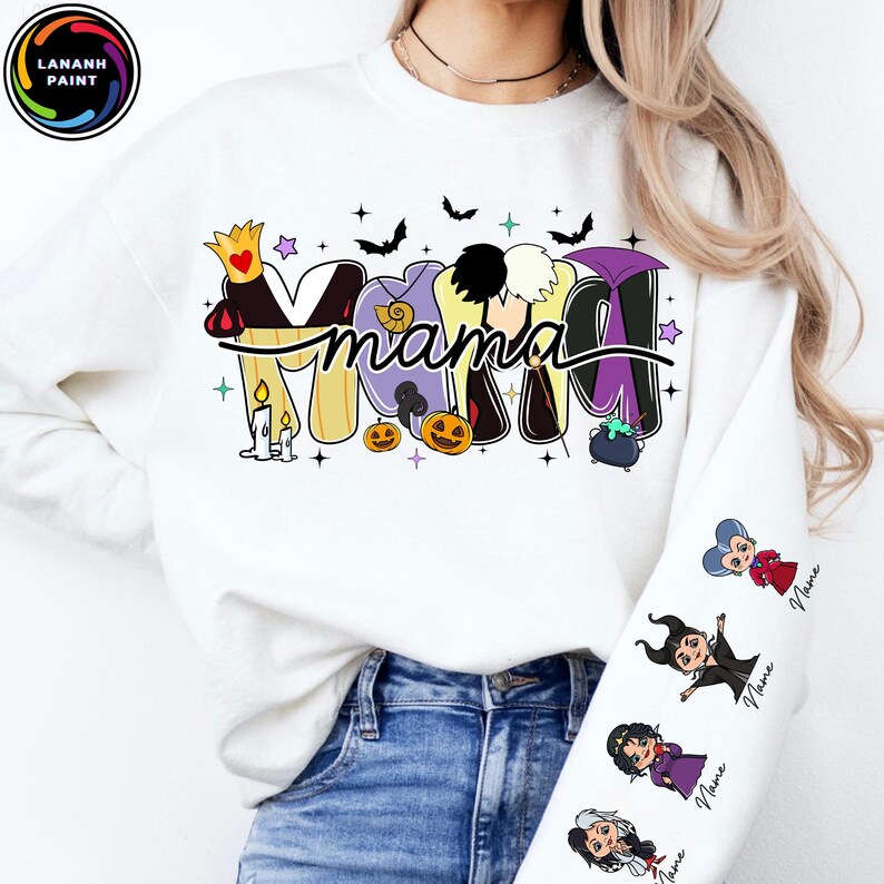 May include: White sweatshirt with the word "Mama" in a Halloween-themed design. The design incorporates cartoon images of villains, bats, pumpkins, and stars. The sleeve features cartoon villain characters with the word "Name" below each.