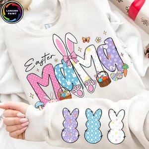 May include: White sweatshirt with the words "Easter Mama" in a colorful design. The letters are decorated with Easter-themed patterns, including polka dots, bunnies, and Easter eggs. Three bunny silhouettes are at the bottom.