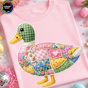 May include: A light pink t-shirt featuring a patchwork duck design. The duck has a green checkered head, a yellow beak and feet, and a body composed of various floral and patterned fabric patches. The shirt has the logo "LANANH PAINT" in a circle.