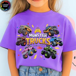 K&ouml;nnte beinhalten: Ein lila T-Shirt mit farbenfrohen Monster-Truck-Grafiken. Der Text "MONSTER TRUCKS ARE MY JAM" ist in einer auff&auml;lligen Schriftart dargestellt. Blitz- und Stern-Akzente erg&auml;nzen das Design. Das T-Shirt wird von einer Person getragen.