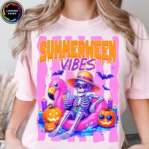Peut inclure: T-shirt rose clair avec un motif coloré. Il représente un squelette portant des lunettes de soleil et un chapeau de paille, se relaxant sur un flotteur flamant rose. Le texte "SUMMERWEEN VIBES" est au-dessus du squelette, avec des citrouilles et des chauves-souris.
