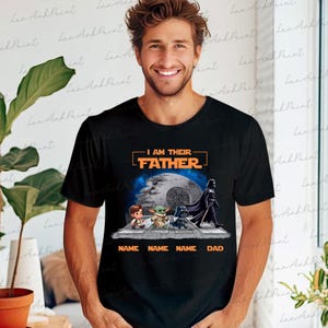 May include: Black t-shirt featuring a graphic with the text "I AM THEIR FATHER" above an image of characters from a popular science fiction franchise. The graphic includes the Death Star and the text "NAME NAME NAME DAD".