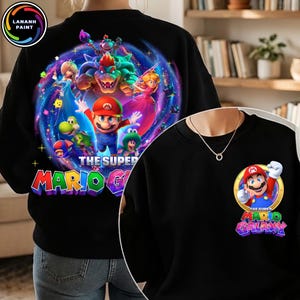 Puede incluir: Sudadera negra con un gr&aacute;fico colorido de Mario y otros personajes del juego Super Mario Galaxy. El dise&ntilde;o incluye el texto "THE SUPER MARIO GALAXY" en una fuente vibrante. Una versi&oacute;n m&aacute;s peque&ntilde;a del dise&ntilde;o est&aacute; en la parte delantera.