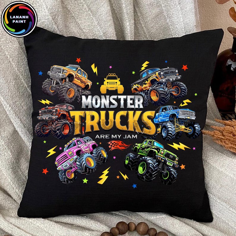 K&ouml;nnte beinhalten: Schwarzes Kissen mit bunten Monster-Truck-Illustrationen, Blitzen und Sternen. Der Text "MONSTER TRUCKS ARE MY JAM" ist in Gelb und Wei&szlig; gehalten. Das Kissen hat ein weiches, strukturiertes Aussehen.