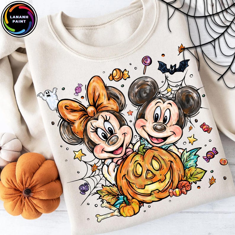 May include: Beige Halloween sweatshirt featuring Mickey and Minnie Mouse with a carved pumpkin. The design includes candy, a ghost, a bat, and spiderwebs. The sweatshirt has a crew neck and long sleeves.