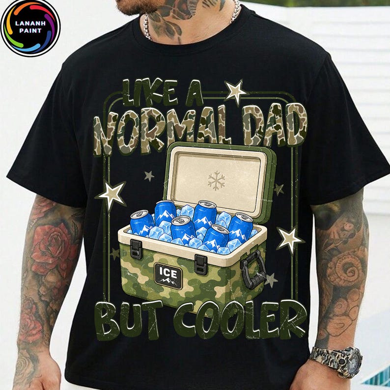 K&ouml;nnte beinhalten: Schwarzes T-Shirt mit dem Text "LIKE A NORMAL DAD BUT COOLER" in Gr&uuml;n und Camouflage-Print. Die Grafik zeigt eine K&uuml;hlbox mit blauen Dosen und Eis, mit Sternakzenten.