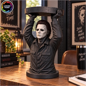 May include: A sculpted bust of a character with a white mask, dark hair, and a dark gray collared shirt, holding a circular black platform above their head with both hands. The figure is depicted from the chest up, featuring a textured finish.