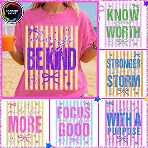 Könnte beinhalten: Rosa T-Shirts mit positiven Botschaften. Eines zeigt "always be kind" in Lila, ein anderes "know your worth" in Grün. Weitere Shirts zeigen "stronger than the storm", "made for more", "focus on the good" und "created with a purpose".