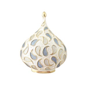 May include: A decorative, teardrop-shaped object with a white base, adorned with blue and silver paisley patterns outlined in gold. The top and base have a gold finish. The object has a small, gold, pointed top.