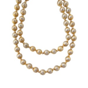 May include: A gold-toned beaded necklace with a brushed finish. The necklace is made of round beads and is double-stranded.
