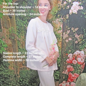 May include: White pajama set with long sleeves and pants. The top has a lace trim around the neckline. The measurements are listed for the top and pants.