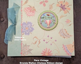 May include: A square scrapbook kit featuring a light green cover with a floral pattern in pink, purple, and orange. A 3-dimensional floral vase emblem is centered on the front. A sheer blue ribbon is tied on the left side. Text reads: Rare Vintage Brenda Walton Chelsea Ribbon design K&Company 12x12" Scrapbook kit Never used.