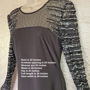 May include: Black dress with sequined sleeves. The dress has a sheer neckline and sleeves embellished with silver and black sequins. Measurements: Bust 81 cm, waist 71 cm, hip 86 cm, full length 91 cm.