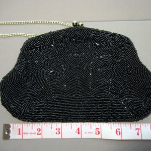 May include: A black beaded evening bag with a gold chain strap. The bag is approximately 7 inches wide.