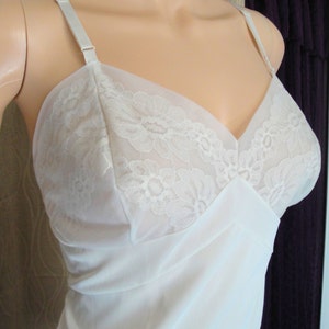 May include: White lace lingerie slip with adjustable straps. The slip has a delicate floral lace pattern and a V-neckline.
