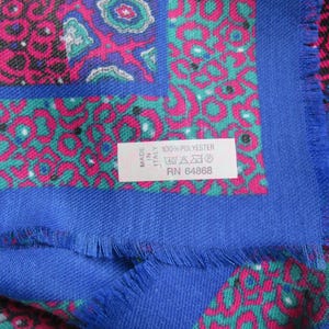 May include: A blue and pink patterned scarf with a white tag that reads "Made in Italy 100% Polyester RN 64868".