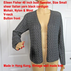 May include: Black mohair, nylon, and wool cardigan sweater with a V-neck and button front. The sweater is sheer and has a textured knit. The label reads "Eileen Fisher 40 inch bust Sweater, Size Small sheer Italian yarn black cardigan Mohair, Nylon & Wool V-neck Button front Made in Hong Kong, Vintage well made knit".