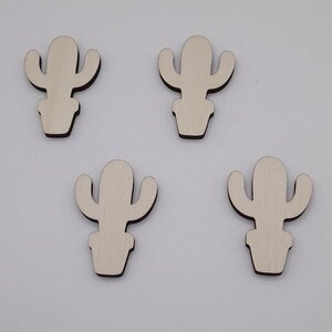 May include: Four identical light-coloured wooden cactus cutouts, each featuring a central stem with two side arms and a small pot base. The wood grain is visible on the surface of each piece, and the edges are dark, creating a distinct outline.